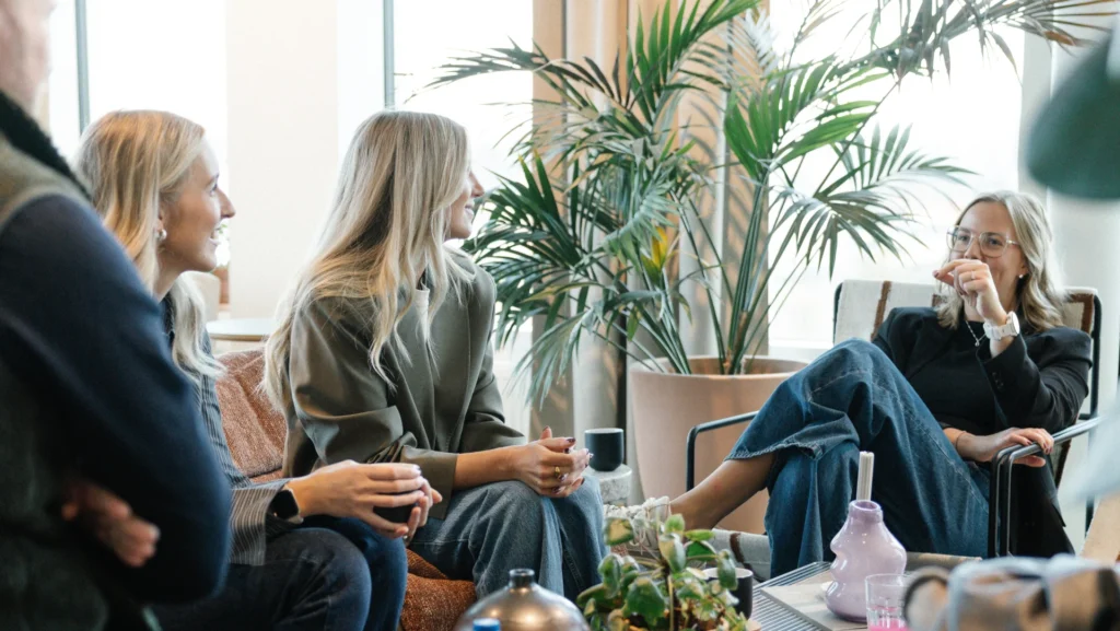 I ett ljust rum med stora fönster och krukväxter sitter fyra personer och småpratar och ler medan de håller i drinkar. Den avslappnade, vänliga atmosfären speglar den kreativa andan hos Reklam & Co byrå i Motala.